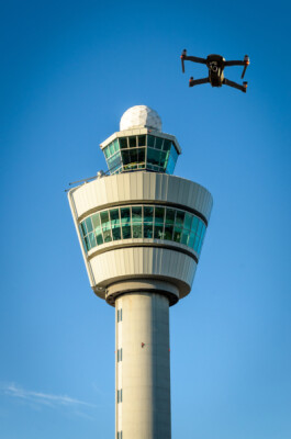 Digital composite of drone and air traffic control tower at airport.