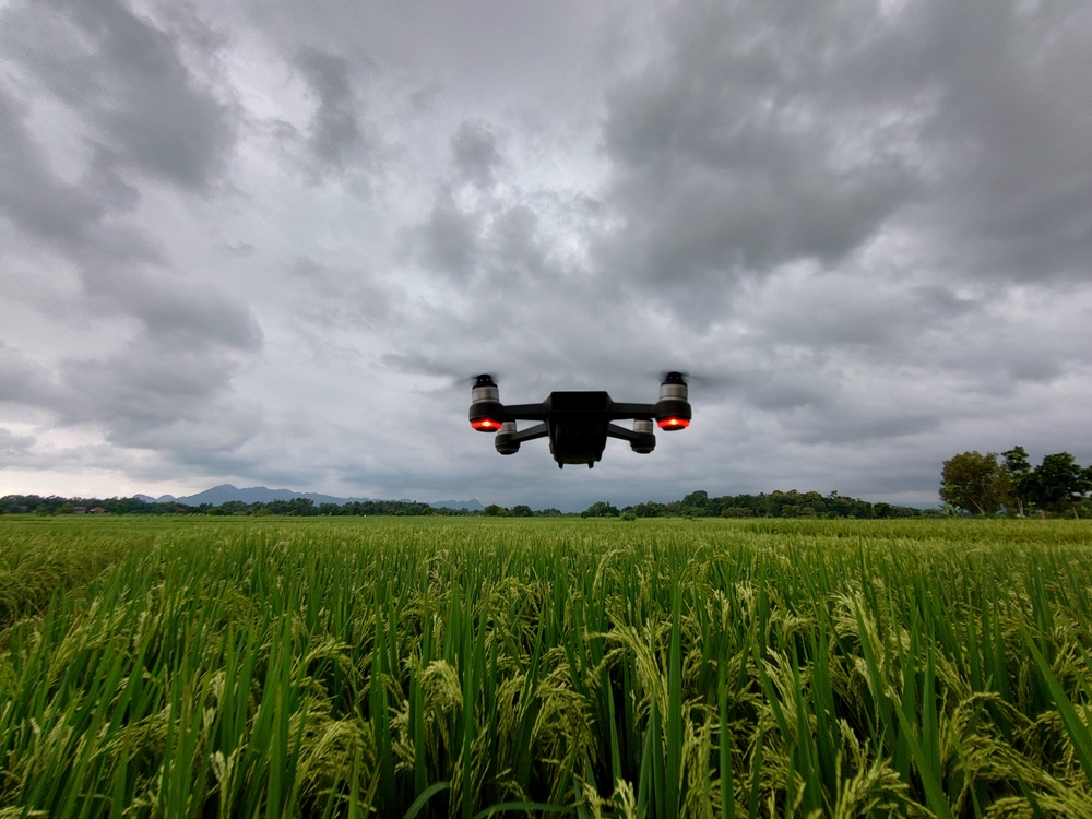 drone flying over tall grass with a sky full of storm clouds above