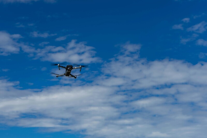 Drone flying in front of partly cloudy sky