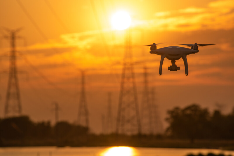Drone surveying High voltage towers the sunset background
