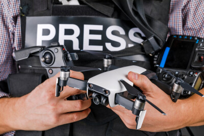 Close-up of man holding drone wearing a "press" vest