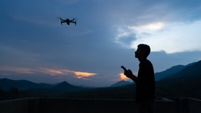 Silhouette of a aerial photographer or traveller flying drone in the nature during the blue hour