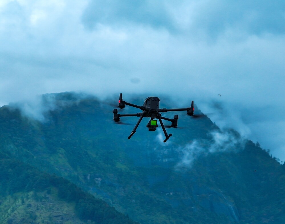 Industrial drone flying through mountains with Lidar sensor payload for aerial surveyor aerial mapping.