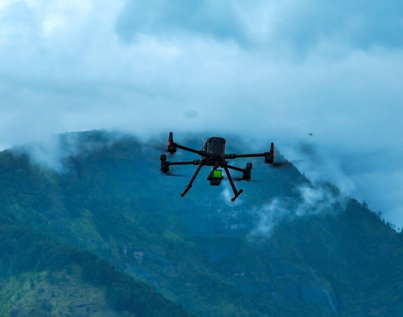 Industrial drone flying through mountains with Lidar sensor payload for aerial surveyor aerial mapping.