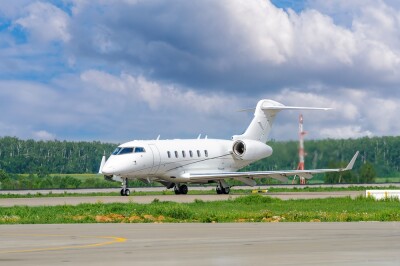 A private white business jet on the runway is preparing for takeoff. Jets of hot exhaust come from jet engines. Jet business aviation