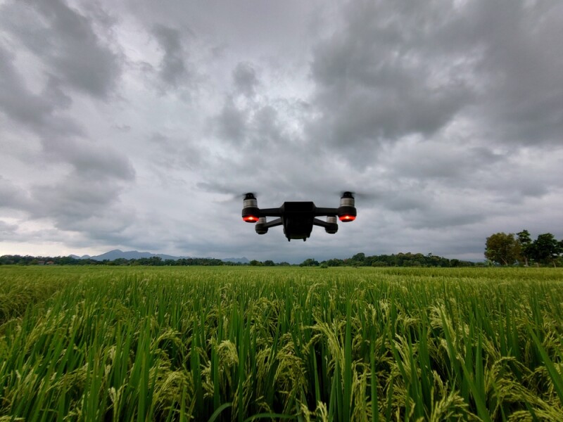 drone flying over tall grass with a sky full of storm clouds above