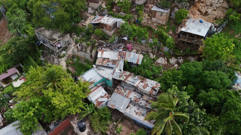 Aerial view of the aftermath of Hurricane Melissa, with storm-damaged homes and rooftops across a hillside neighborhood in Kingston