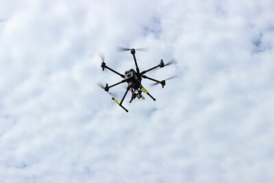 Powerful rescue drone in action over the beach, flying to save lives by lifting a lifebuoy to assist drowning individuals in the sea.