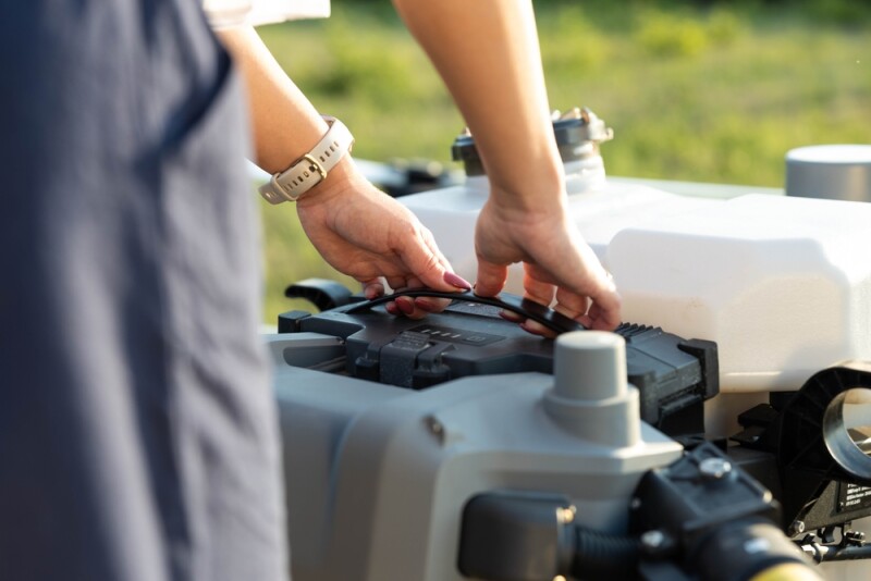 Close-up of a woman's hands holding the battery of a large agricultural drone and placing the battery in the drone housing