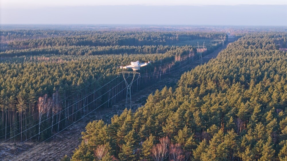 Drone flight over a high-voltage electricity pylon at sunset during winter.