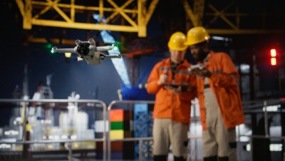 Professional drone operators flies a UAV around a drilling rig, using remote control and camera systems to evaluate the condition and ensure safety on platform, oil production.