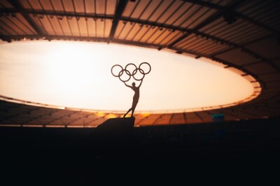 Statue of Athletics Woman Triumphantly Lifts Olympic Circle at Modern Olympic Stadium.