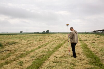 A male surveyor works with a GNSS receiver in the open space