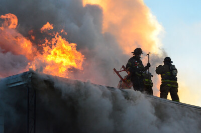 Firefighters on the roof of a house that is on fire