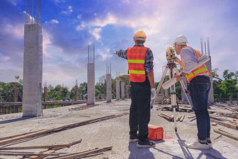 Engineer or surveyor worker working with theodolite transit equipment at outdoors construction site.