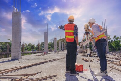 Engineer or surveyor worker working with theodolite transit equipment at outdoors construction site.