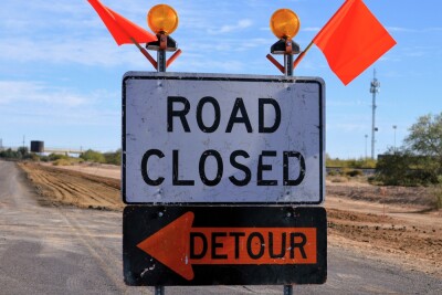 Road closure detour signs and orange caution flags rural Arizona
