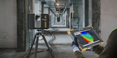 Hand holding tablet that shows 3D scan data from inside a gutted building.