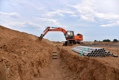 Excavator dig the trenches at a construction site. Trench for laying external sewer pipes. Sewage drainage system for a multi-story building. Civil infrastructure pipe, water lines and sanitary storm
