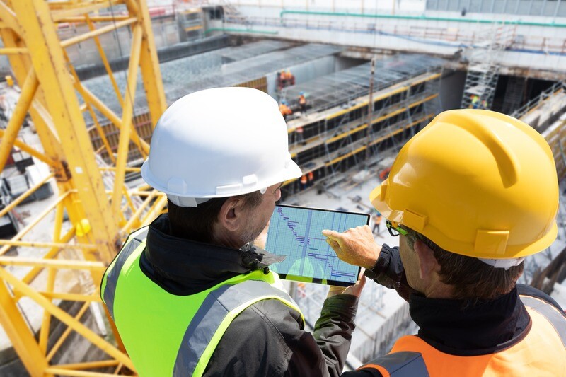 Workers on a construction site looking at a tablet.