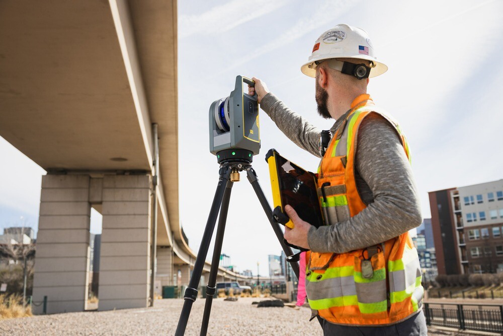 Man using Trimble X9 scanner under a bridge.