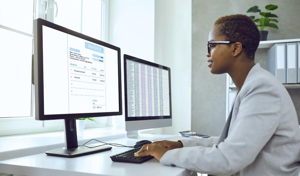 Woman facing her computer screens that contain information on invoices