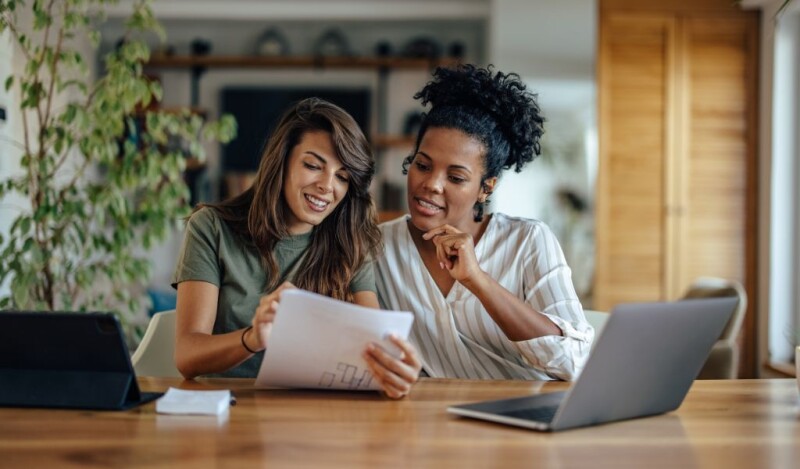 two women coworkers smiling while looking at a piece of paper