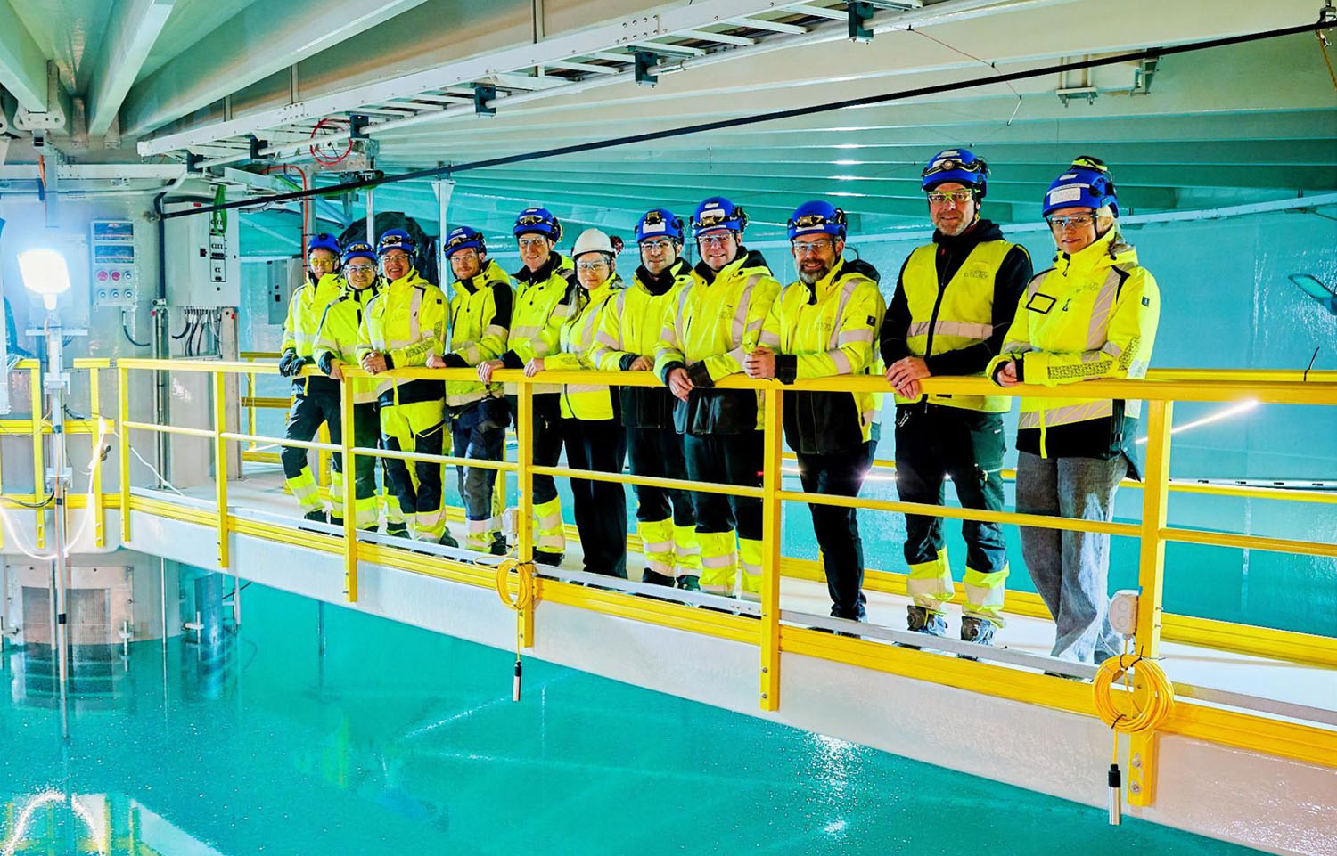 Salmon Evolution employees on the edge of a tank at the firm's Indre Harøy facility