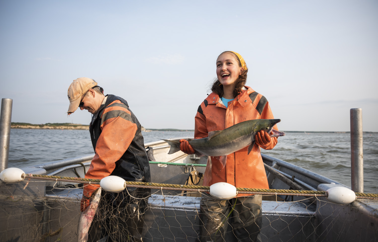 Emily Taylor, a fifth-generation native Alaska salmon fisher, holding a Bristol Bay sockeye salmon in a fishing boat