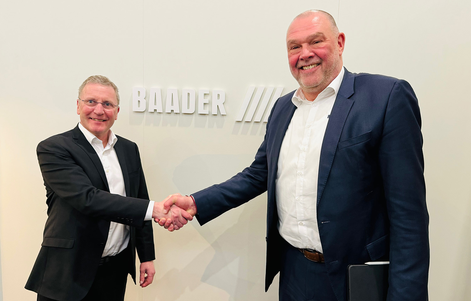 Grieg Director Piotr Wingaard and BAADER Norway Vice President of Sales Modulf Barstad shake hands at BAADER's booth in Barcelona, Spain