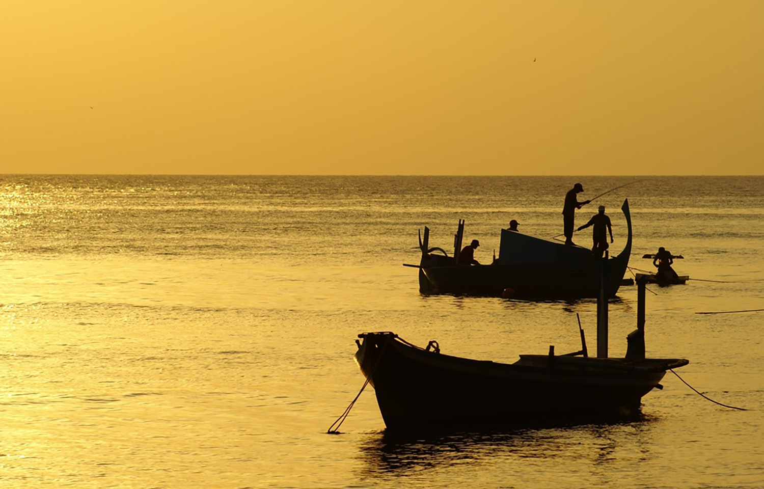 A photo of fishing boats in the Maldives at sunset