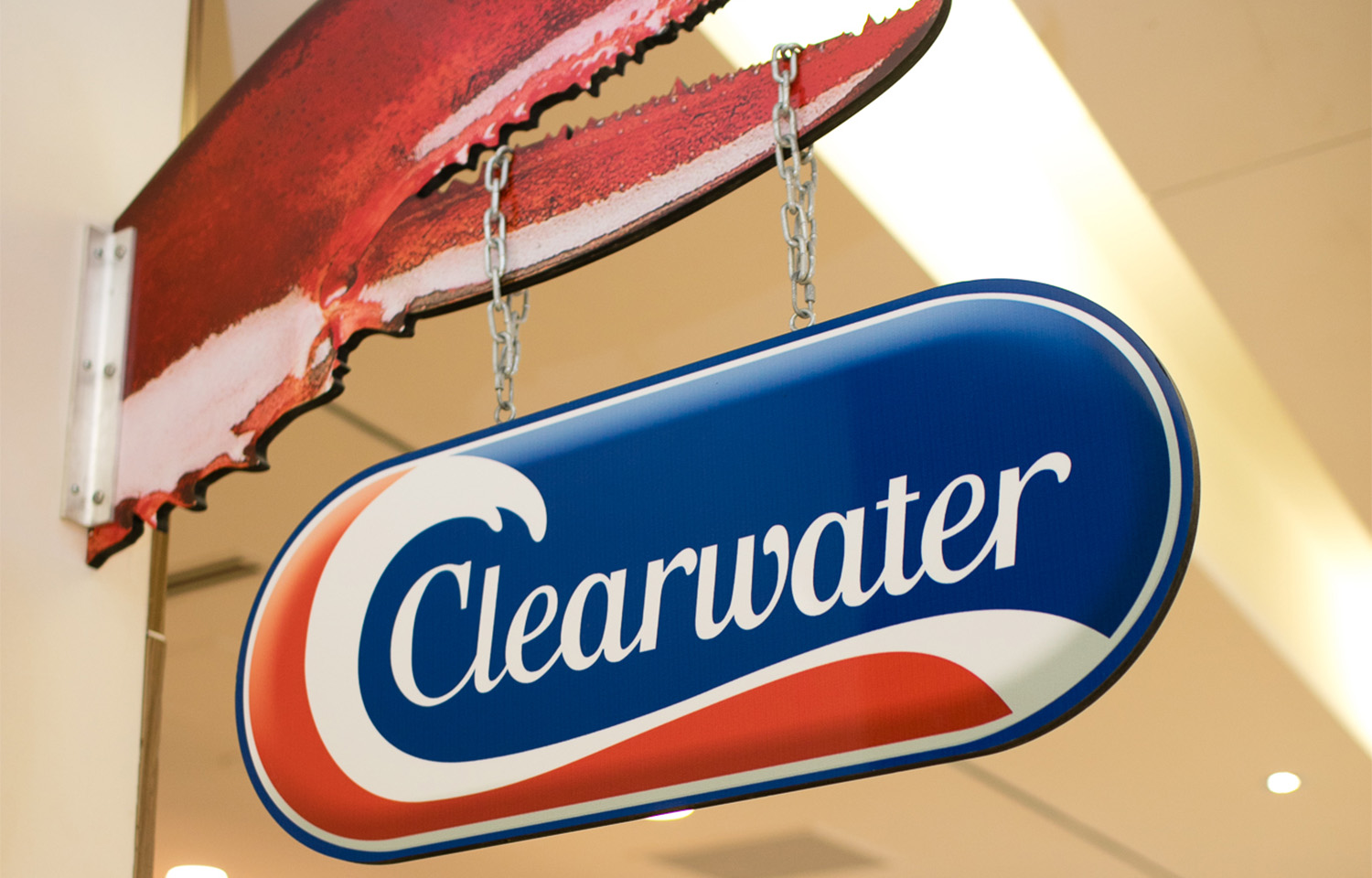 A sign featuring the Clearwater Seafoods logo hanging by chains from a lobster claw