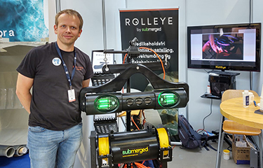 A Submerged employee posing next to a display of the company's Rolleye system.