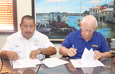 Belize Fisheries Director Rigoberto Quintana signs a settlement agreement with a Rainforest Seafoods representative.