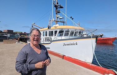 Diane Lebouthillier, the new Minister of Fisheries, Oceans, and the Canadian Coast Guard, in front of a fishing boat.