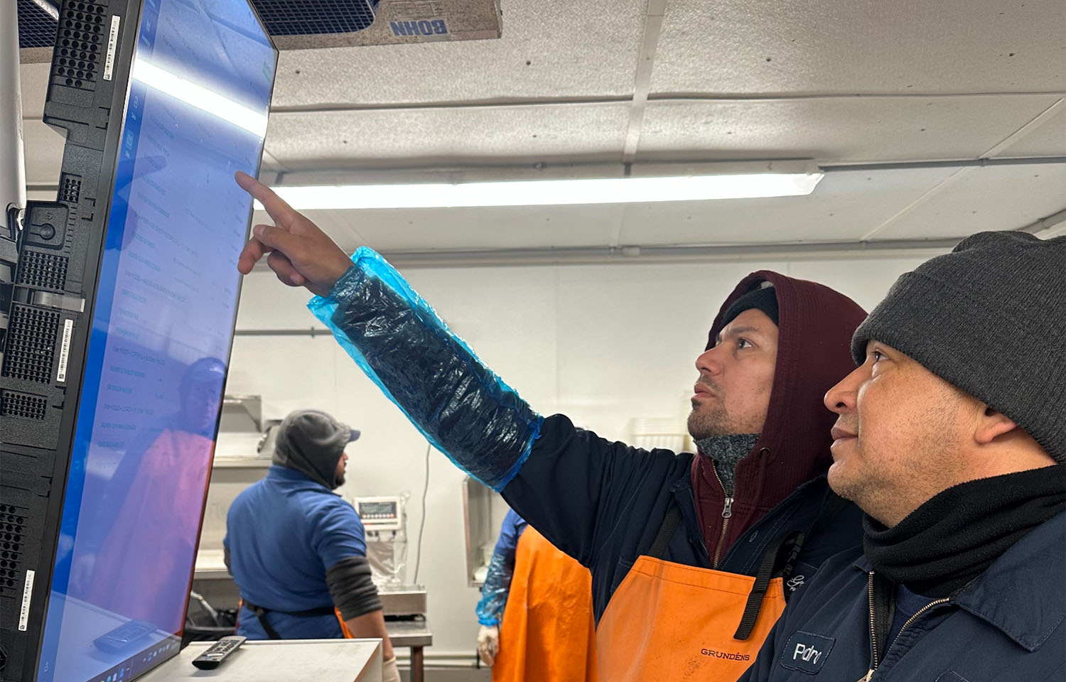 Two men pointing at a screen including a BlueTrace interface