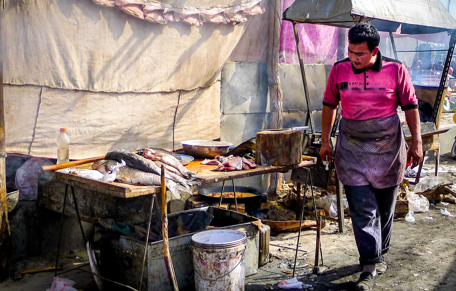A Uyghur man grills fish at the Yopurga weekly market near Kashgar in China's Xinjiang Uyghur Autonomous Region