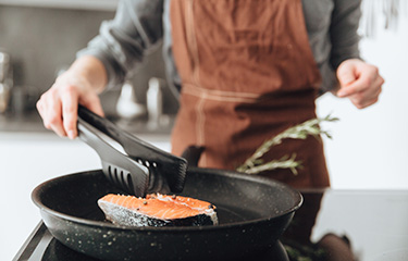 A woman cooking a salmon steak.