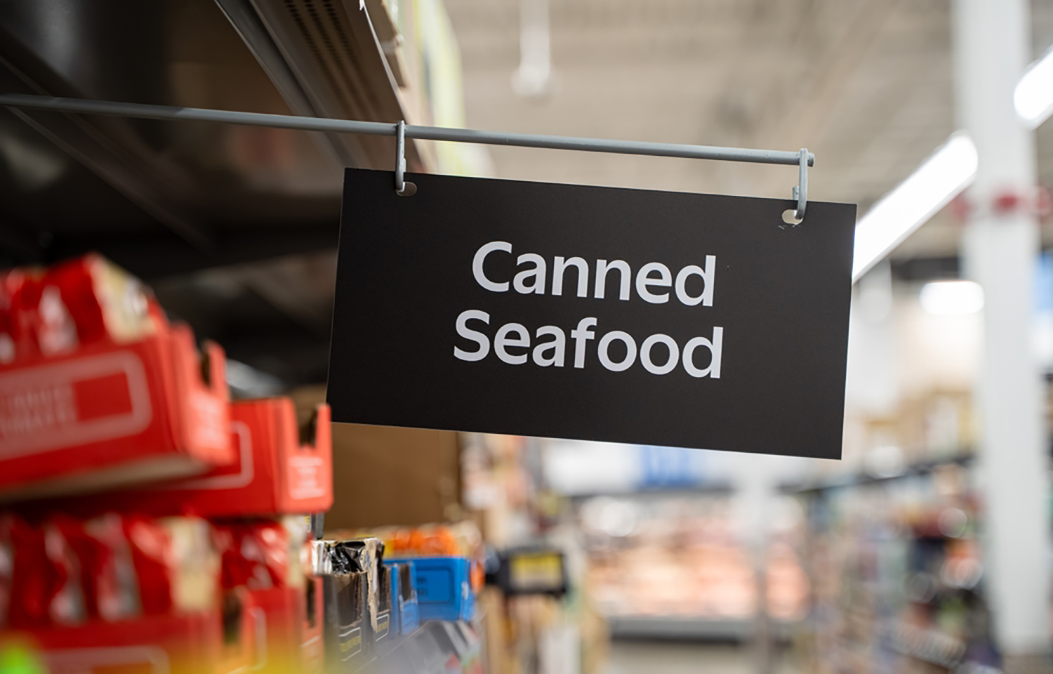 A canned seafood sign in a grocery store