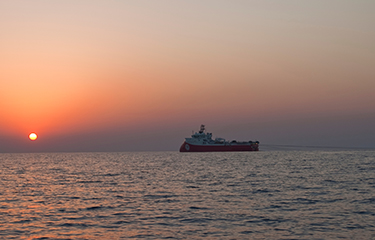 A fishing vessel at sea during a sunset.