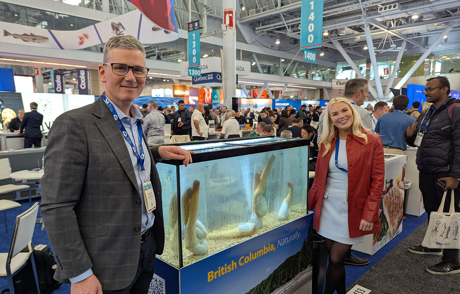 Underwater Harvesters Association Executive Director Grant Dovey and Marketing Manager Katie Lindsey posing near a tank of geoduck at Seafood Expo North America