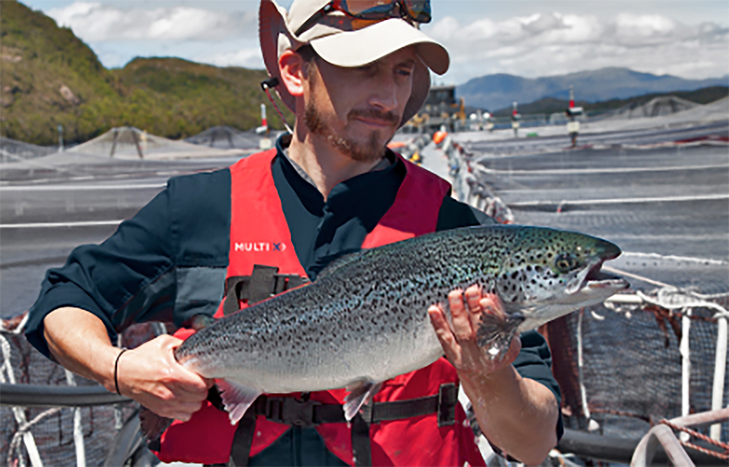 A Multi X farmer holding a salmon grown on one of the company's farms