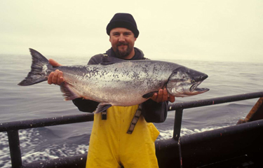 A fisherman holds a large salmon.
