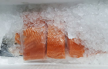 Norwegian salmon fillets in packaging on ice.