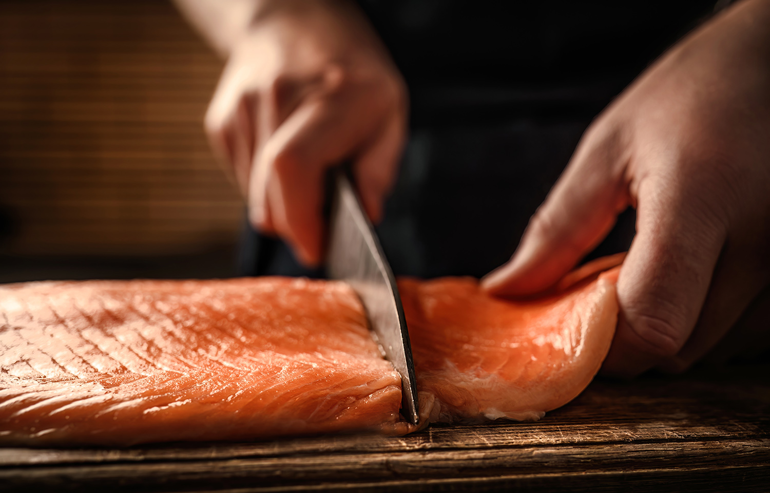 A chef cutting a fillet of salmon