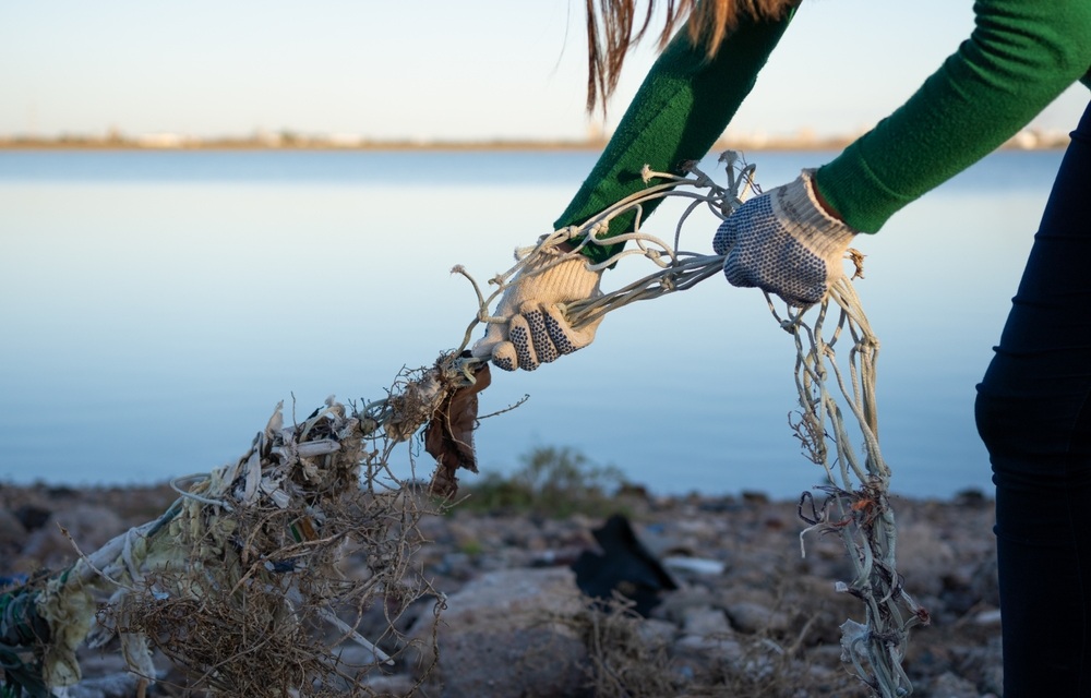 A person removing fishing waste from a beach