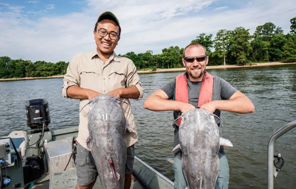 Two fishermen holding large blue catfish