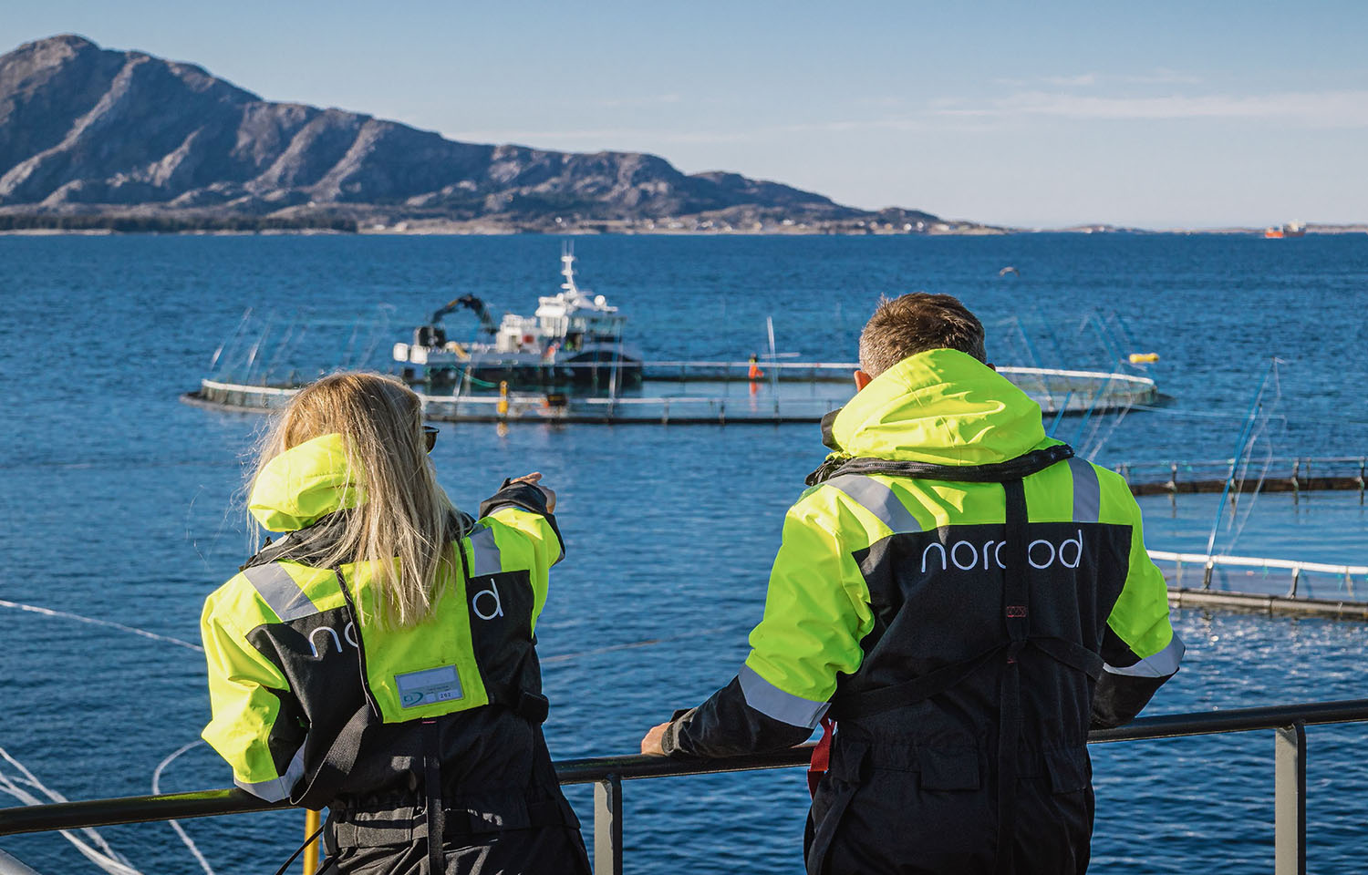 Two people standing on a Norcod net pen