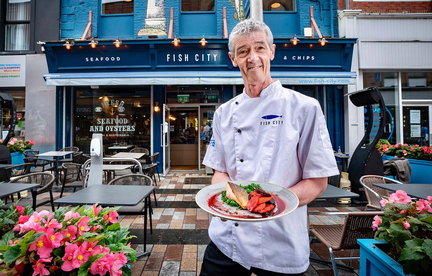 John Lavery posing with a dish of seafood outside his restaurant Fish City