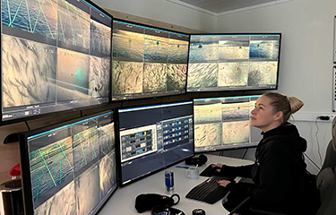 An Ice Fish Farm worker observing salmon farms on computer screens.